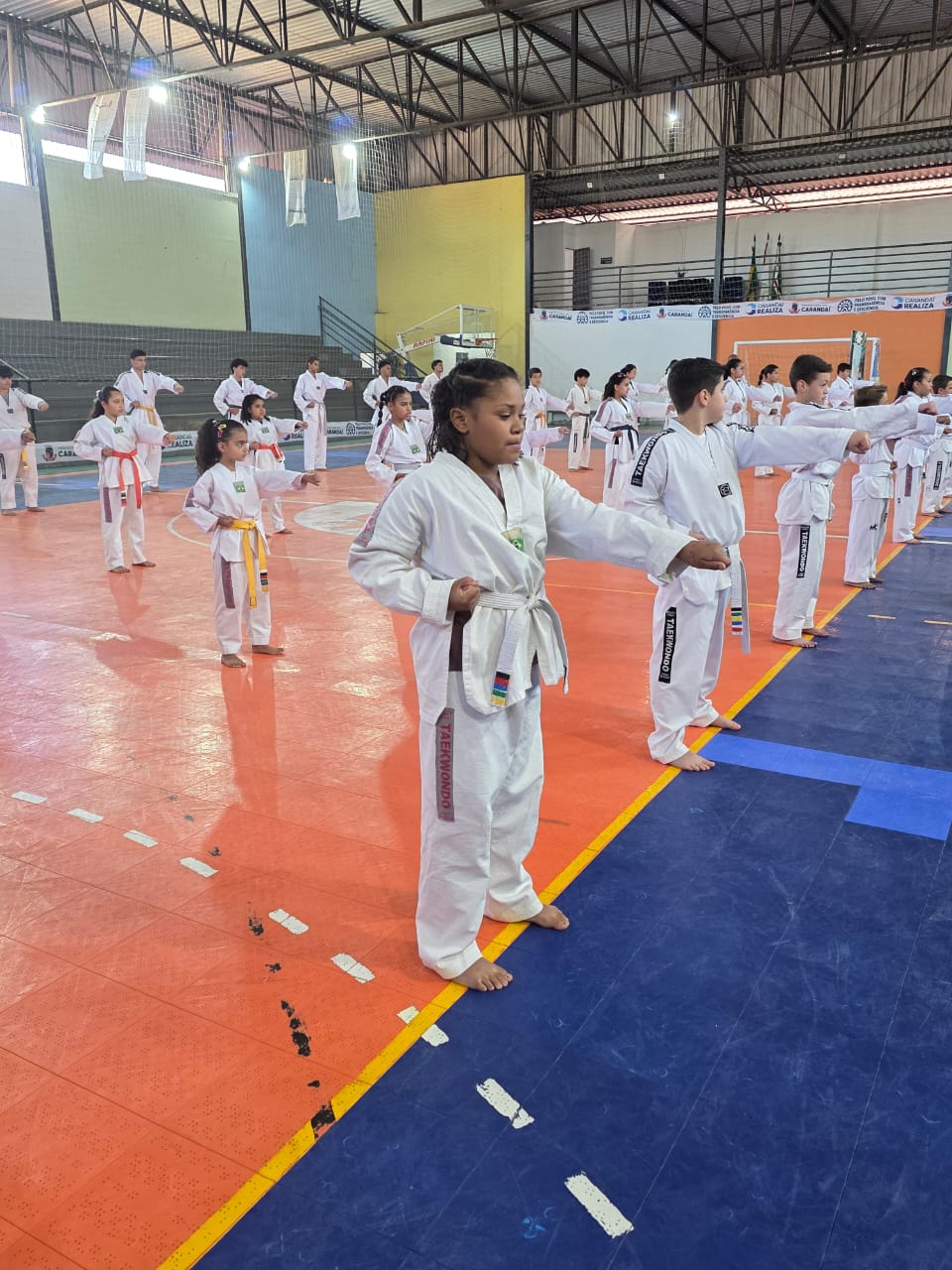 Aluna treinando golpes com a turma ao fundo
